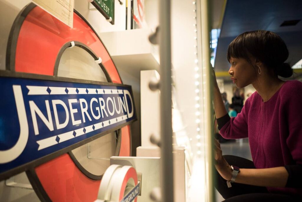 Woman closely examining a London Underground sign at the London Transport Museum exhibit