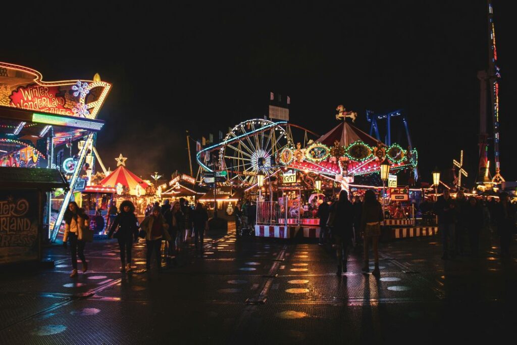Brightly lit rides, Ferris wheel, and Christmas market stalls at Winter Wonderland in Hyde Park, London, during the festive season.